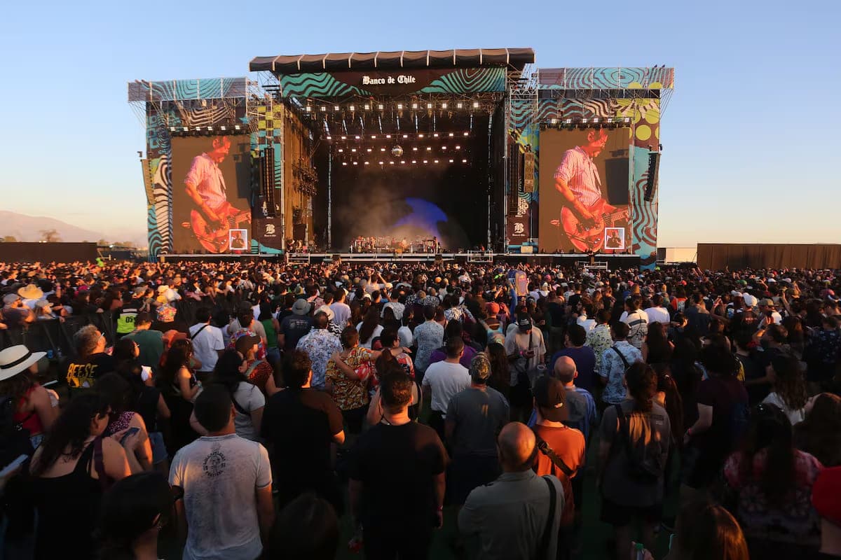 A vibrant crowd at Lollapalooza Chile in Parque O'Higgins, stage lights at dusk