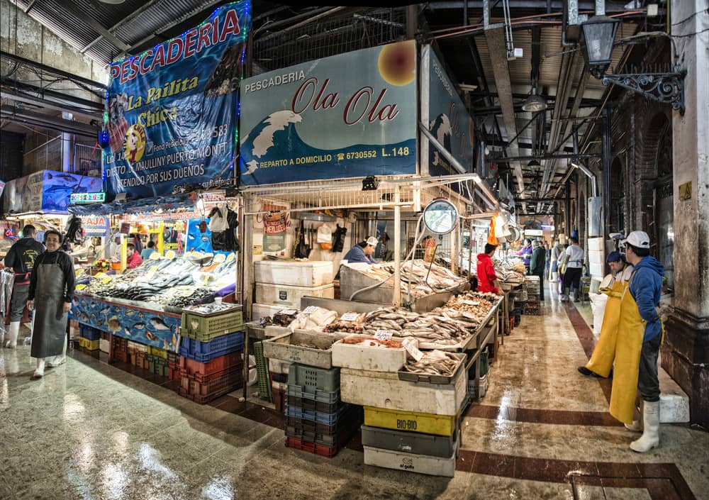 A busy market street in Santiago with locals shopping, stalls full of fresh produce.